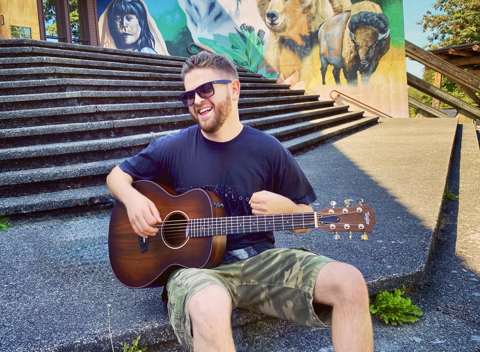 Nick Kolar playing acoustic guitar outdoors