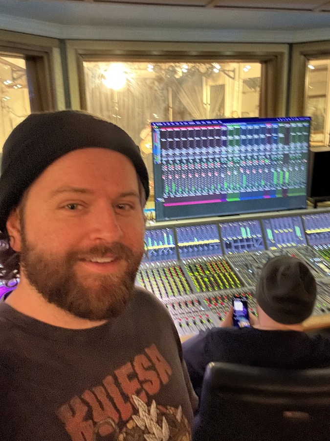 Nick in a control room behind a large mixing console